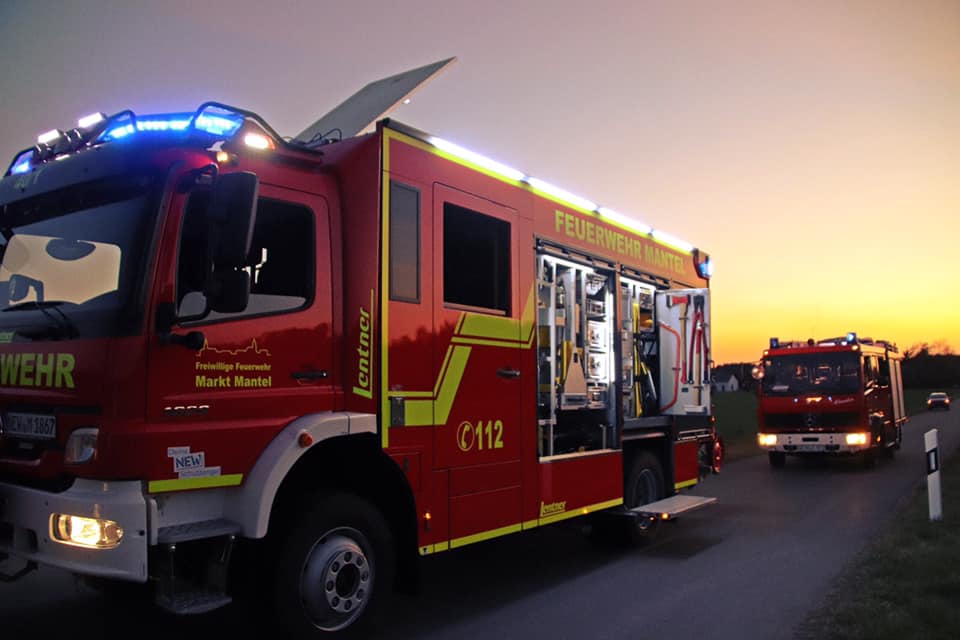 Löschgruppenfahrzeug LF 40/1 der Feuerwehr Mantel mit Blaulicht bei Sonnenuntergang auf Einsatzfahrt